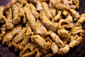 seasoned chicken cooking in frying pan